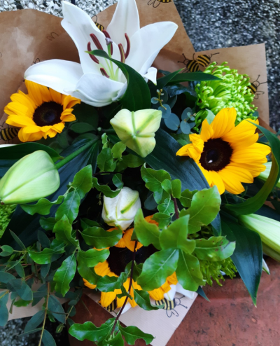 Ray of sunshine - Sunflowers and lilies are the basis for this beautiful bunch of kraft paper wrapped blooms, tied with raffia.